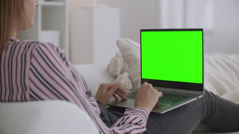 student-woman-is-chatting-online-by-laptop-with-green-screen-for-chroma-key-technology-resting-at-home-at-weekends